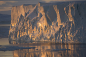 Textured tabular iceberg reflecting in the Weddell Sea at sunset in October with grease ice. Antarctica