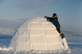 John Ululijarnaat, an inuit hunter, uses a snow knife to finish an igloo he has built. Igloolik, Nunavut, Canada. 1993