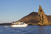 Dive boat by Pinnacle Rock, the eroded remains of a tuff cone, by the the volcano on Isla Bartolome. Galapagos. Ecuador