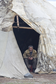 Nikolai Votgyrgin, an elderly Chukchi reindeer herder, sitting by the entrance to his Yaranga (tent) at a summer camp. Iultinsky District, Chukotka, Siberia, Russia