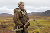 Sasha Takui, A Chukchi reindeer herder, working with his reindeer at their autumn pastures. He is holding a curved throwing stick (Kenunen), which he uses to change the direction his reindeer are going. It is similar to a Boomerang. Iultinsky District, Chukotka, Siberia, Russia