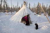 Pavla Nogo, a Komi woman, in the entrance of her reindeer skin tent at a winter camp. Yamal, Northwest Siberia, Russia