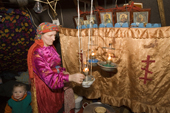 Pavla, a Komi woman, lights oil lamps in her tent. Religious icons are in the background. Yamal, NW Siberia, Russia