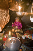 With the light from oil lamps, Pavla Nogo, a Komi woman, sews a reindeer skin boot in her tent. Yamal, Northwest Siberia, Russia