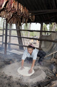 Lena Kuboleva, a young Selkup woman, making traditional Selkup bread by baking dough in hot sand at her family's summer camp in the forest. Krasnoselkup, Yamal, Western Siberia, Russia.