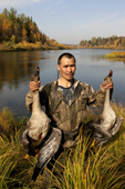 Vassily Kargachev, a Selkup hunter, holds up two geese he has shot for food on the River Shirta in the autumn. Krasnoselkup, Yamal, Western Siberia, Russia