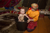 Marina Valeeva, a Komi woman, bathes her young daughter Albina in a plastic bucket inside their tent at a winter camp. Yamal, Westren Siberia, Russia