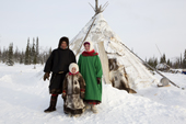 A Komi couple, Nikolai Valeev and his wife Marina together with their daughter Anastasia, outside their reindeer skin tent at a winter camp. Yamal, Western Siberia, Russia