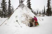 Marina Valeeva, a Komi woman, stands at the entrance to her family's tent at their winter camp in the forest. Priuralsky District, Yamal, NW Siberia.