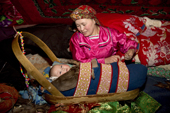 Marina Valeeva, a Komi woman,settles her 6 month old baby, Tonya, in her cradle, at a winter camp in the forest. Priuralsky District, Yamal, NW Siberia.