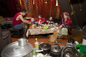 Nikolai Valeev and his wife, Marina, a young Komi couple, having an evening meal with their children inside their family's tent at a winter camp in the forest. Priuralsky District, Yamal, NW Siberia.