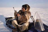 An Inuit hunter using an Iridium satellite phone on the Melville Peninsula. Nunavut, Canada. 1999