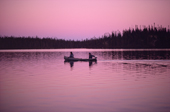 Cree trappers return from a hunting trip in their canoe at twilight. Quebec, Canada. 1988