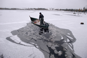 Abel Brien, a Cree hunter, breaks the ice on a frozen lake with his boat. Quebec. Canada. 1988