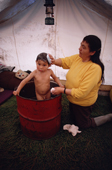 Johnnie, Cree boy is given a bath in an oil drum at a bush camp by his grandmother, Elizabeth Brien. Northern Quebec. Canada. 1988