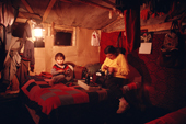 Cree family in their 'bush camp' cabin at night, lit by oil lamps. Quebec. Canada. 1988