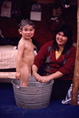 Cree boy at a camp is given a bath in a bucket by his mother. Lake Bourinot Quebec. Canada. 1988