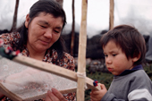 Cree woman, Elizabeth Brien, makes a snow shoe watched by her grandson. Quebec, Canada. 1988