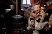 Saibore Momde, a Nganasan elder, smokes his pipe while relaxing in a hut at a camp on the Kheta River. Taymyr, Northern Siberia, Russia. 2004
