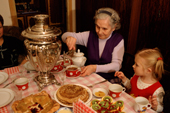 Watched by her great grandaughter Sasha, Anna Chikunova pours hot water from a Samovar. Moscow, Russia. 2002