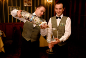 Fyedor & Aleksei, waiters at the Petrov Vodkin restaurant in Moscow pour Vodka from a large bottle into a glass. Russia.
