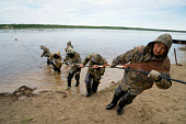 A group of Nenets fishermen, wearing protective anoraks against mosquitoes, haul in their fishing net on the River Taz. Tazovsky region, Yamal, Northwest Siberia, Russia